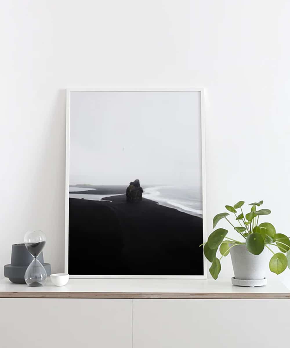 Une photo d'une formation rocheuse touchée par l'océan sur la plage noire, photographiée en Islande.